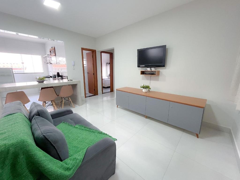a living room with a couch and a tv on a wall at Residencial Tijuco - Apto 204 in Diamantina