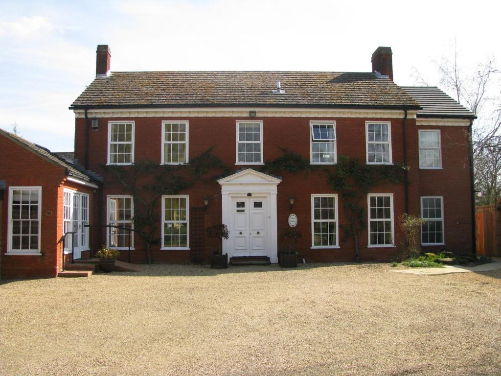 a large red brick house with a white door at B&B The Pippins in Sandy