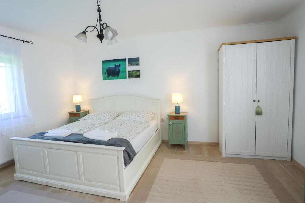 a bedroom with a white bed and two night stands at Fekete Gólya Fogadó Gemenc in Szekszárd