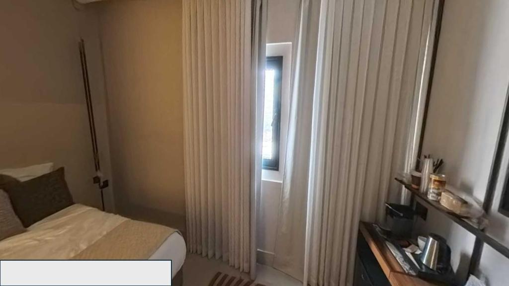a small bedroom with a bed and a window at Metro Hotel Herzliya in Herzliyya B