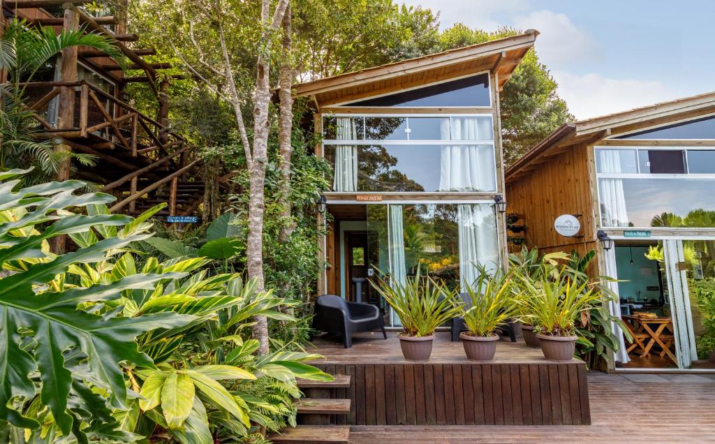 a house with glass doors and plants at Moradas do Vale Praia do Rosa in Praia do Rosa