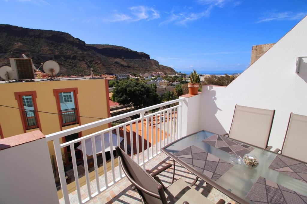 a balcony with a glass table and chairs at Las Cascadas Puerto de Mogán II in Puerto de Mogán