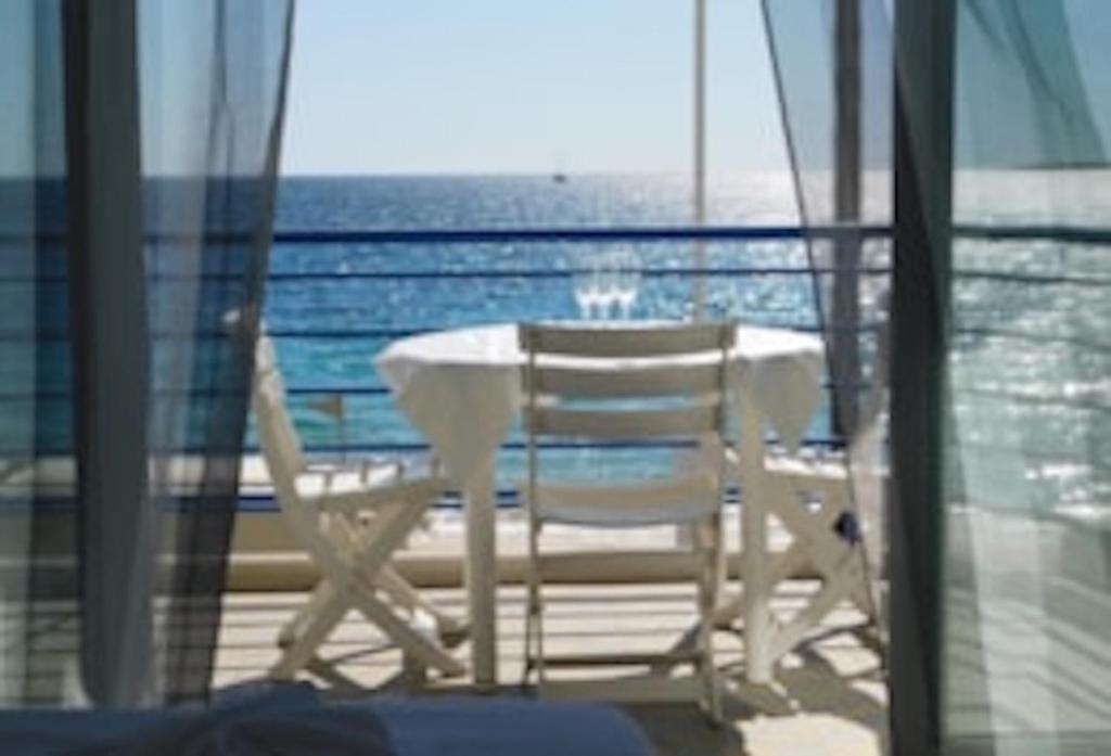 Ein Tisch und Stühle auf einem Balkon mit Meerblick in der Unterkunft La caravelle in Juan-les-Pins