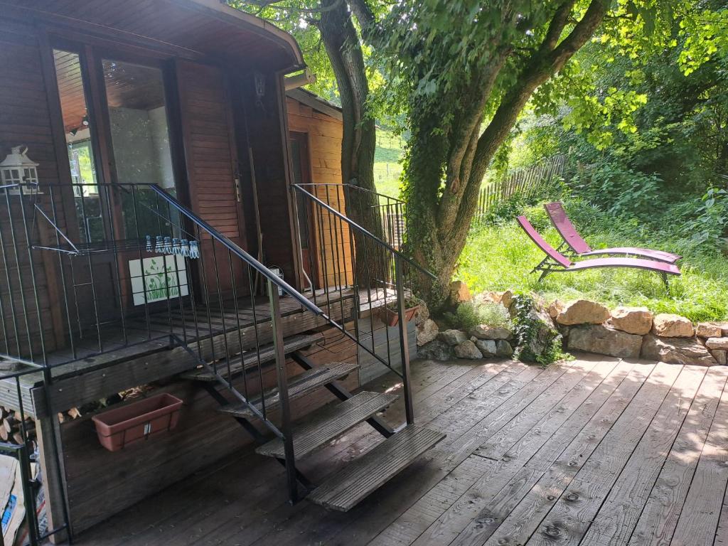 a porch of a cabin with a staircase and a bench at Roulotte champêtre à la ferme in Rochefort-Sanson