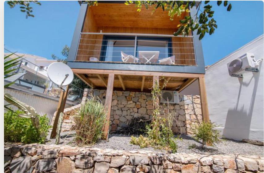 a house with a stone wall in front of it at Tiny house in São Brás de Alportel