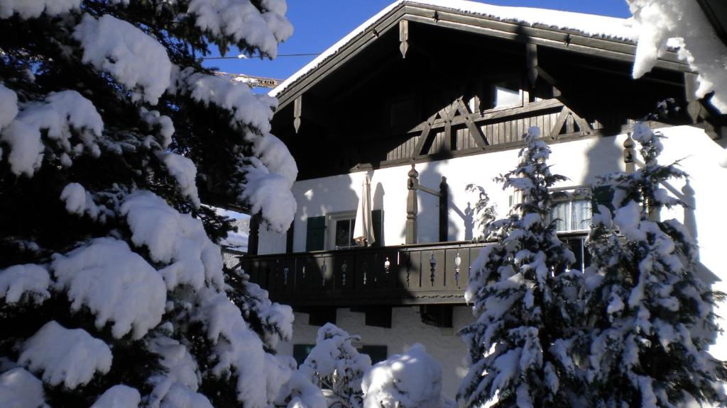 a snow covered building with a balcony and a tree at Alpenlodge in Garmisch-Partenkirchen