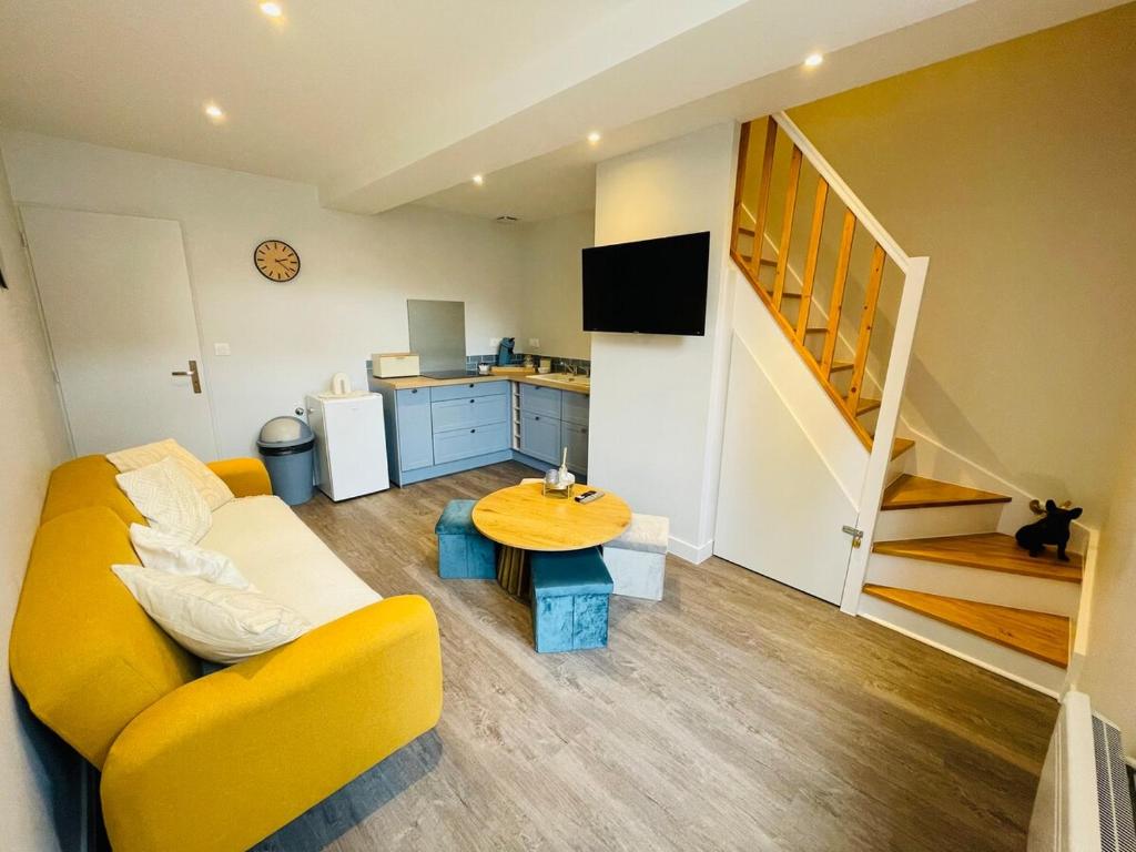 un salon avec un canapé jaune et une table dans l'établissement La Cabane, à Hesdin