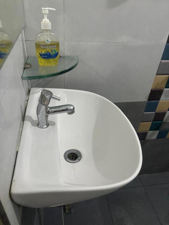 a white sink in a bathroom with a bottle of soap at Sapthagiri Euphoria in Chikmagalūr