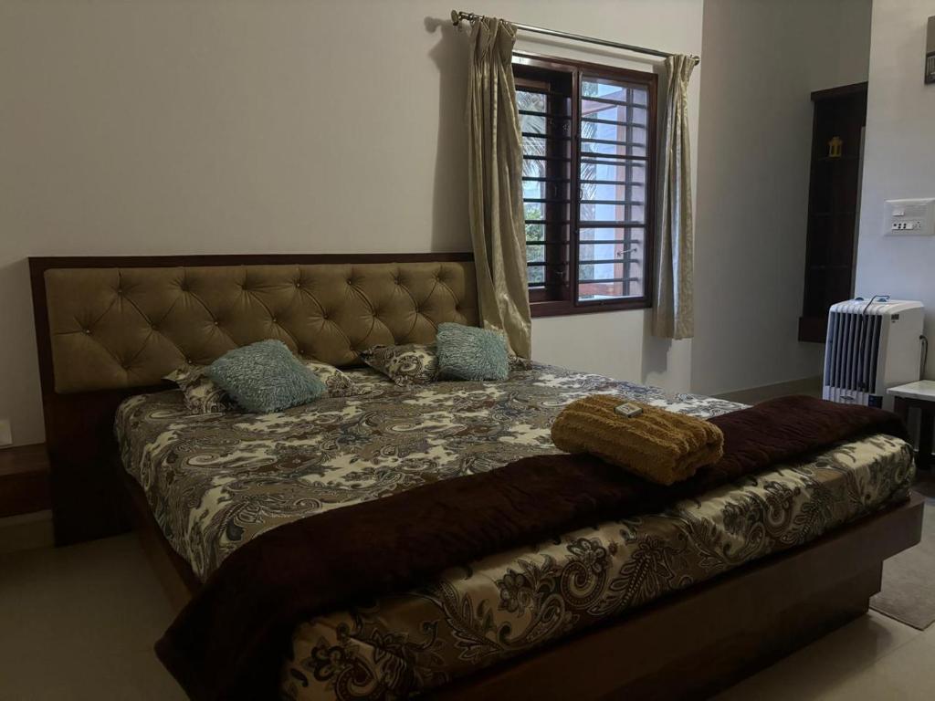 a bedroom with a bed with a blanket and a window at Sapthagiri Euphoria in Chikmagalūr