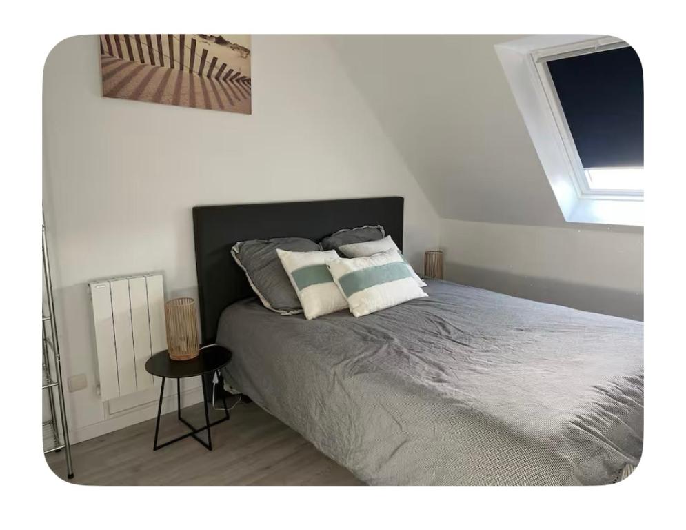 una camera da letto con un letto con due cuscini sopra di Maison dans les dunes a Le Touquet-Paris-Plage