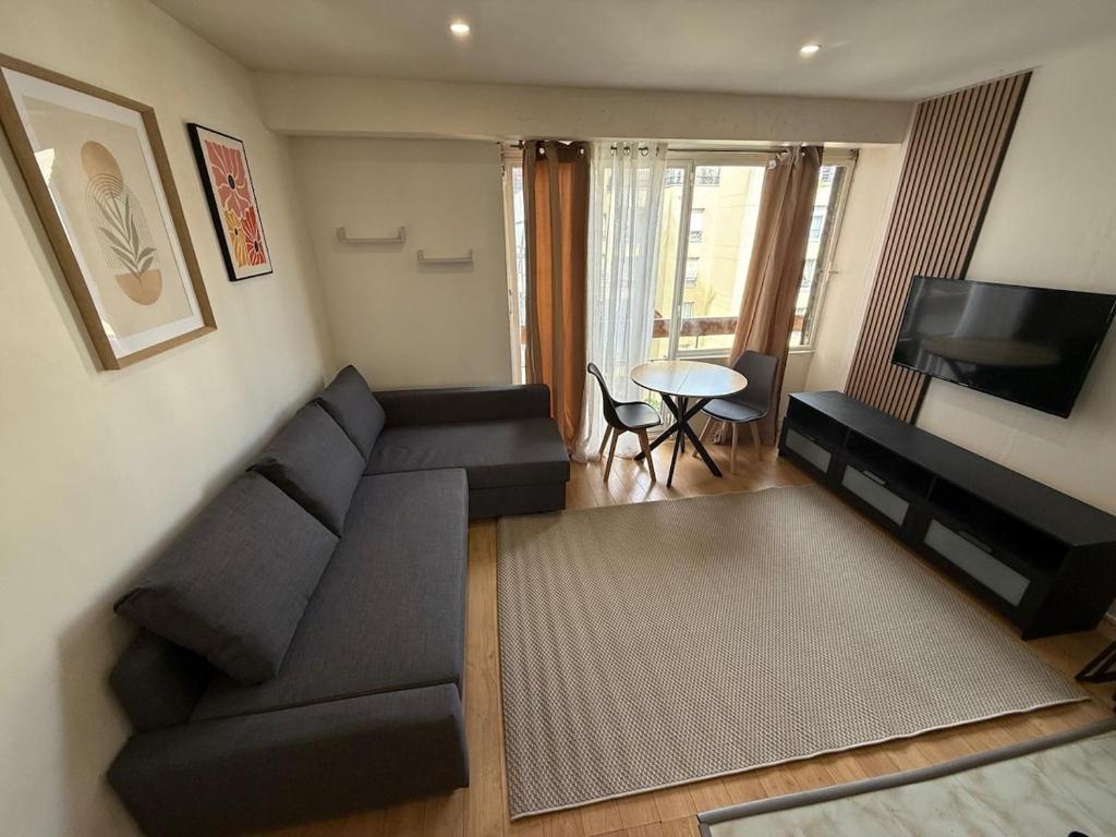 un salon avec un canapé noir et une télévision dans l'établissement Cozy Studio Ideally Located, à Paris