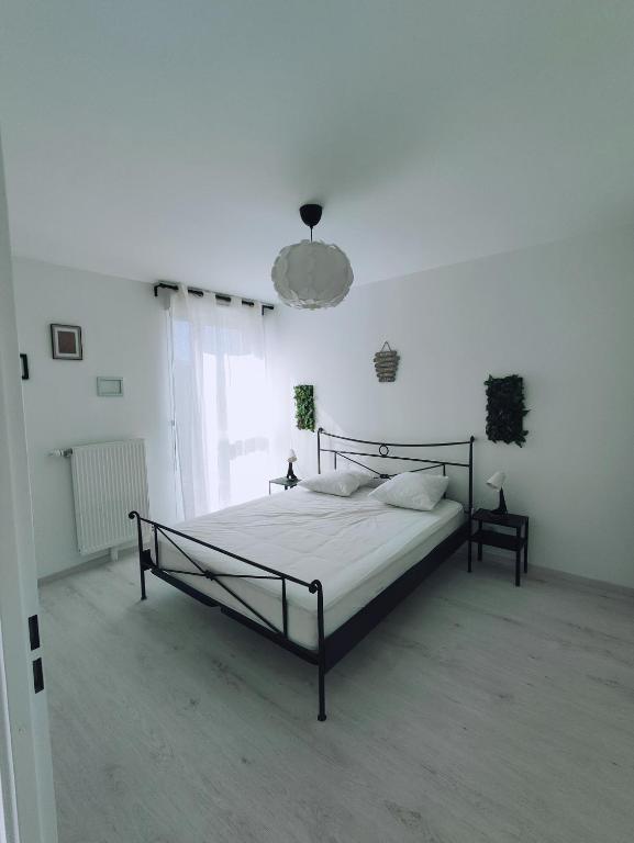 une chambre avec un lit dans une pièce blanche dans l'établissement Joli appartement DISNEY Paris, à Bussy-Saint-Georges