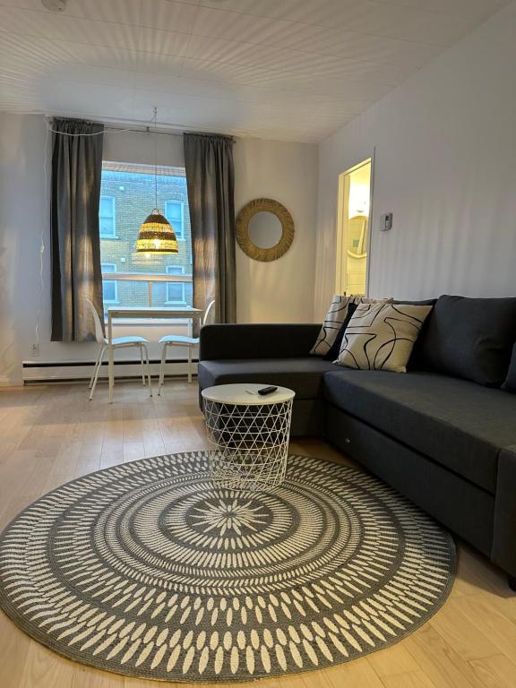 a living room with a black couch and a rug at Petit hôtel Limoilou Studio B - Cozy et central in Quebec City