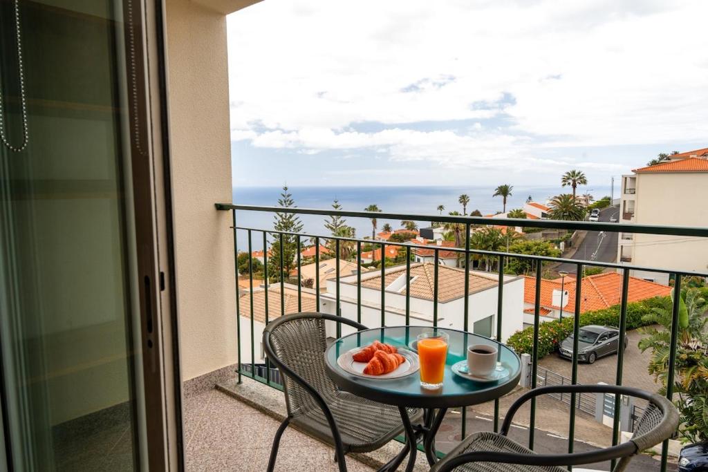 a table with a plate of food on a balcony at Garajau Sea View in Caniço