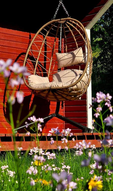 a hanging chair with pillows in a yard with flowers at gemütliches TinyHouse im Naturpark in Rorodt