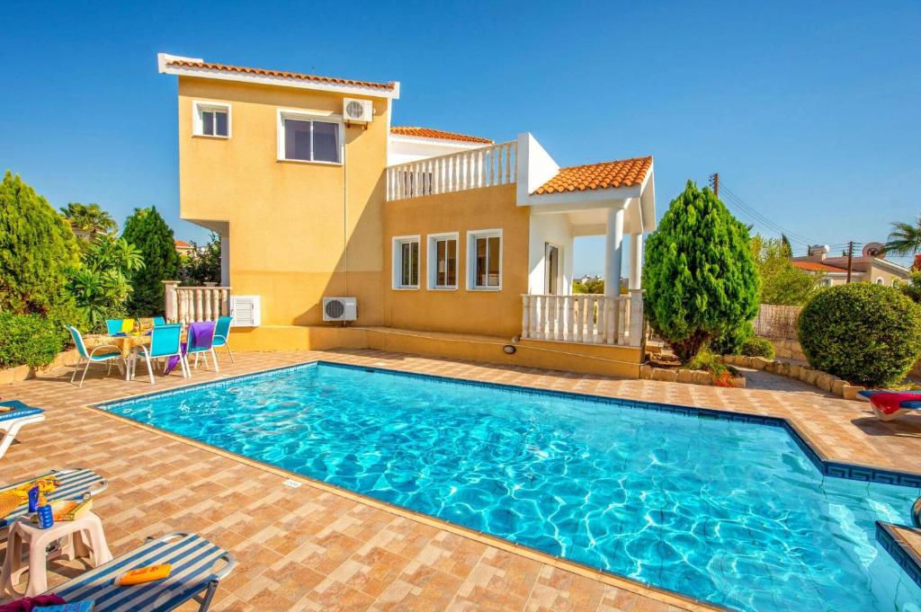 a villa with a swimming pool in front of a house at Villa Gardenia by Villa Plus in Peyia