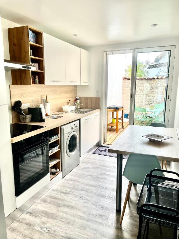 La cuisine est équipée d'une table, d'un évier et d'un lave-vaisselle. dans l'établissement Maison de vacances à Oléron, à Saint-Denis-dʼOléron