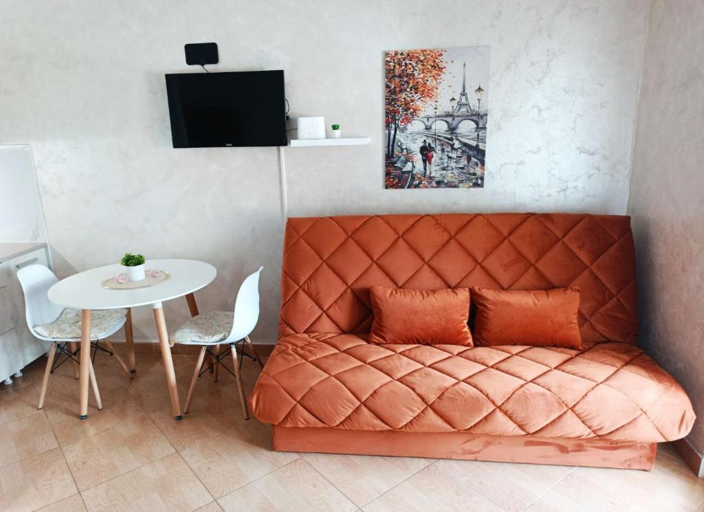 an orange bed in a room with a table at Zevs Apartmani 2 in Igalo