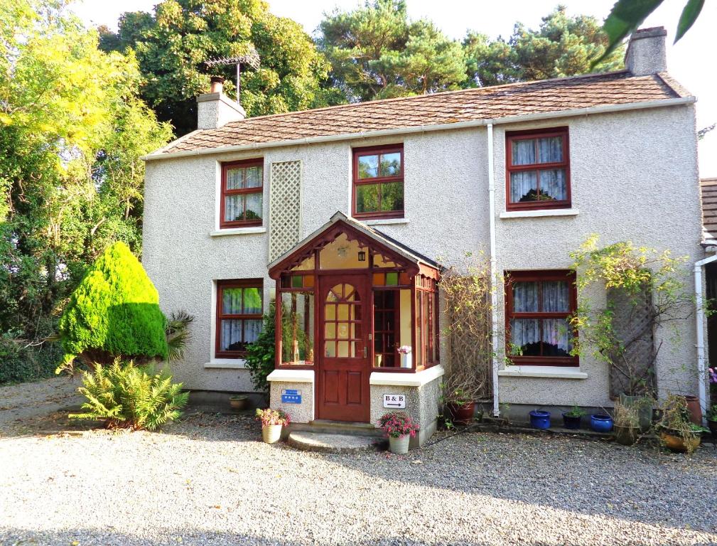 ein kleines weißes Haus mit einer Holztür in der Unterkunft Ballacowell Cottage in Sulby