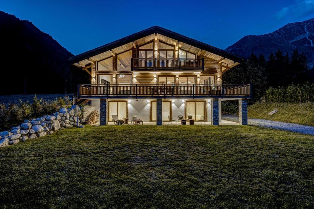 une grande maison en bois avec une terrasse sur une pelouse dans l'établissement Chalet Freya, à Chamonix-Mont-Blanc