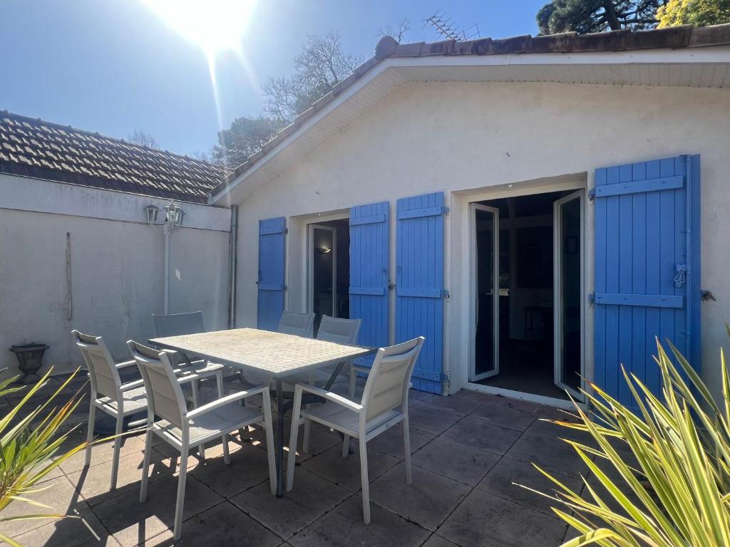 a table and chairs on a patio with blue doors at Maison volets bleus - jusqu'à 9 personnes - 3 chambres - Arcachon Centre in Arcachon