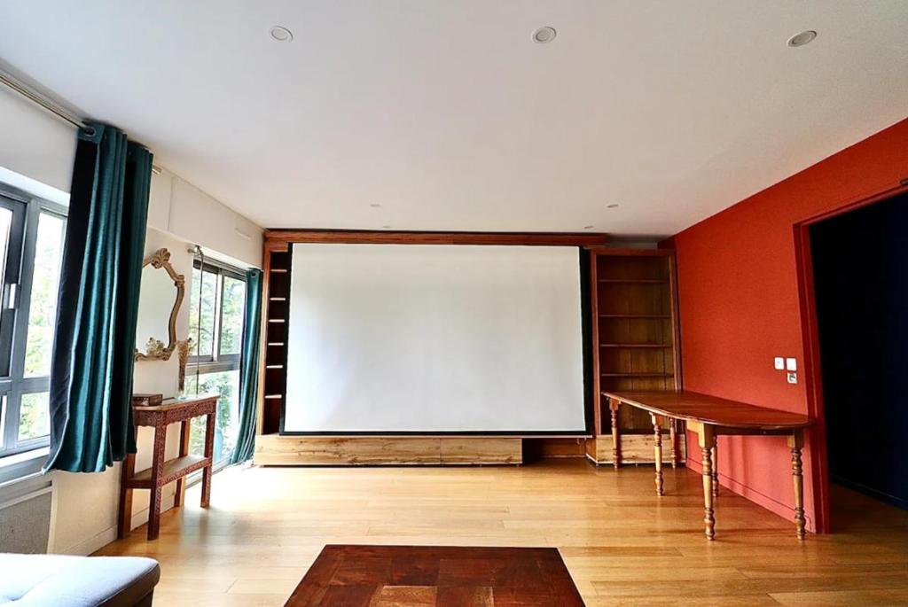 Cette chambre est dotée d'un grand écran blanc sur le mur. dans l'établissement Beautiful 3 rooms in a serviced apartment, à Paris