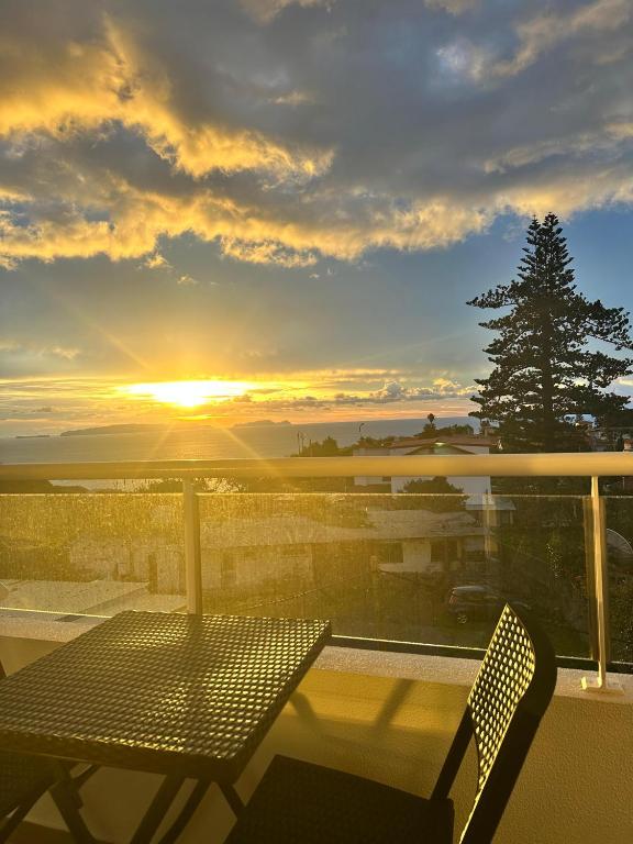a table and chairs on a balcony with the sunset at Prestige Solmar - Sea View Apartment - Free covered parking - Caniço Center in Caniço