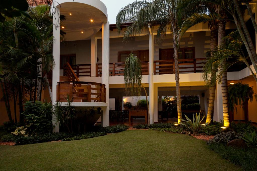 a building with palm trees in front of a yard at Hotel Westfalenhaus in Asuncion