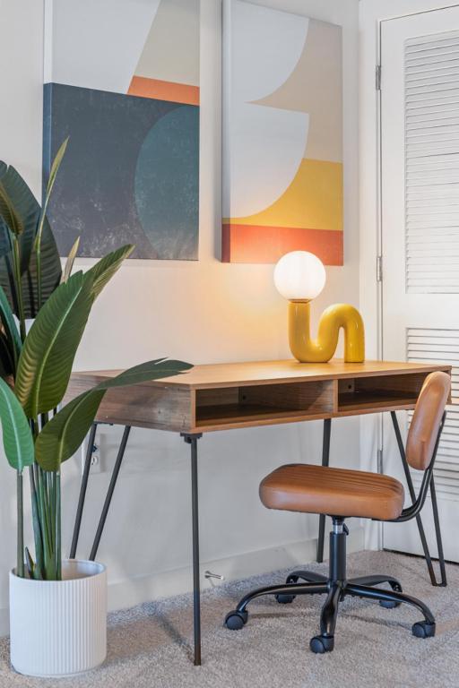 a wooden desk with a chair and a plant at King and Queen 2-Story Loft with 2 Ensuite Baths and Private Balcony at Atlantic Station in Atlanta