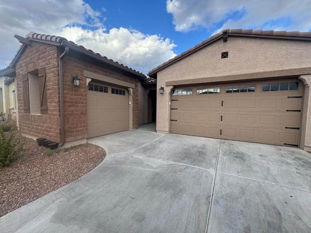 une maison avec deux portes de garage et une allée dans l'établissement genie palace at statefarm stadium, à Phoenix