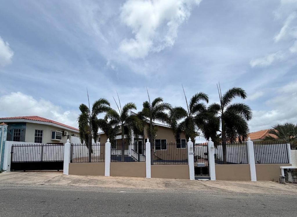 a white fence in front of a house with palm trees at Aqua Villa in Willemstad