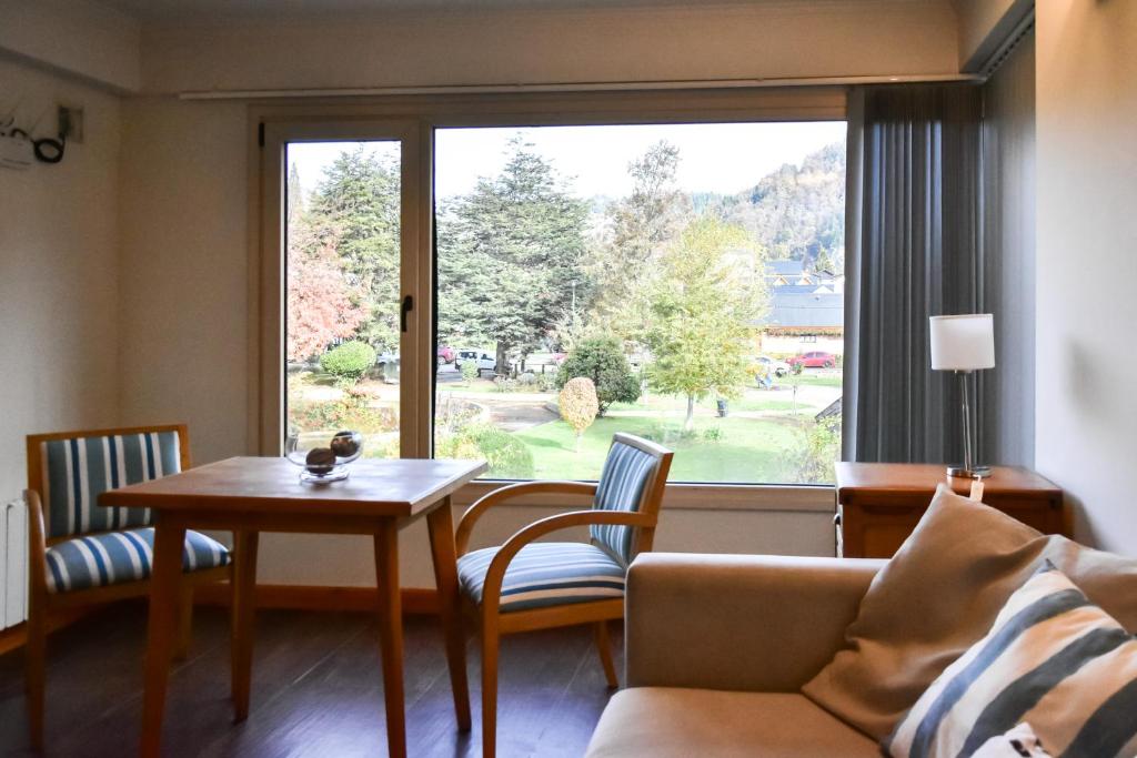 a living room with a couch and a table and a window at Departamento Centenario con hermosa vista in San Martín de los Andes