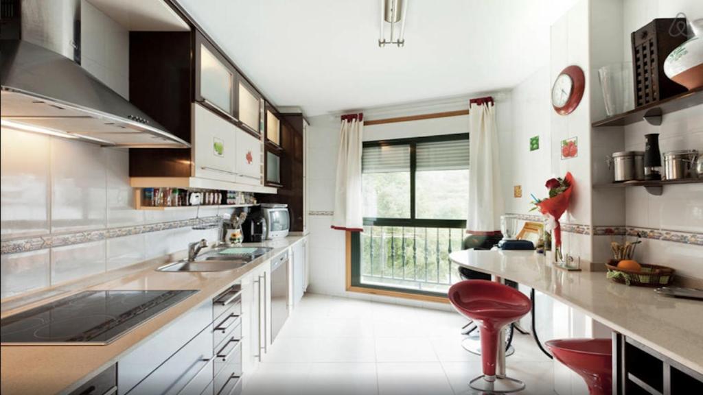 eine Küche mit weißen Arbeitsflächen und einem großen Fenster in der Unterkunft Altavista Apartment in Raxo