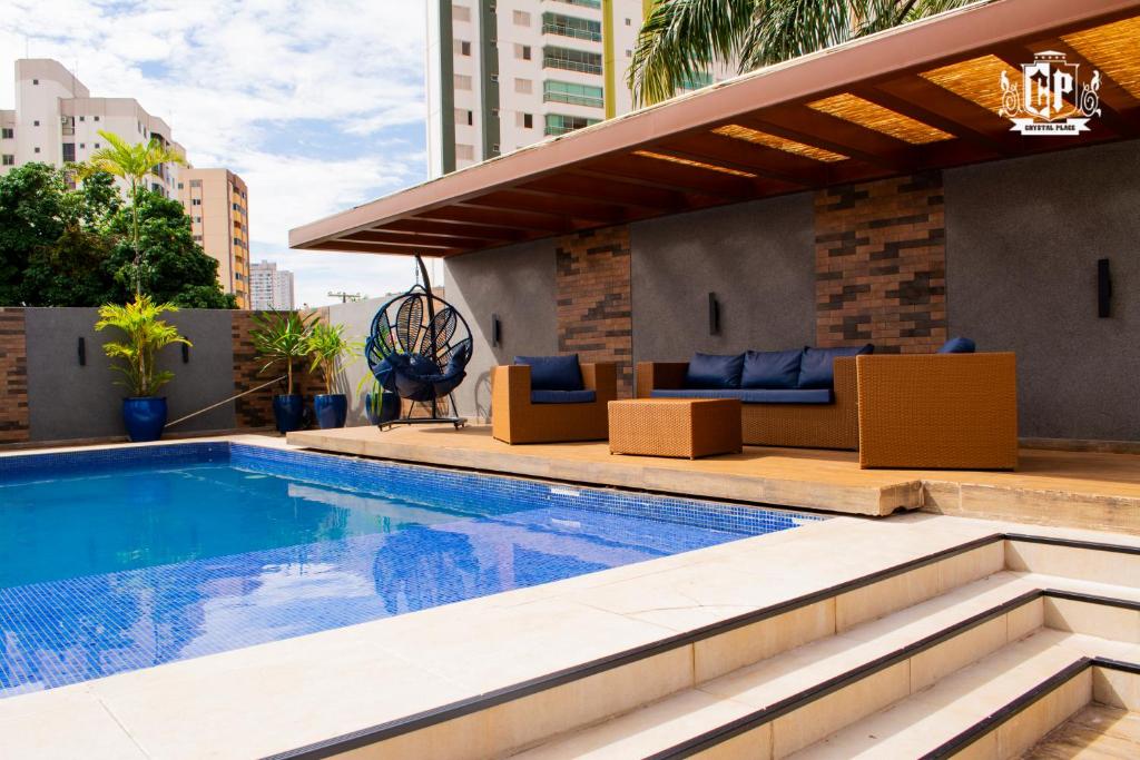 a swimming pool with a patio furniture and a building at Edificio Crystal Place Ap1405 in Goiânia