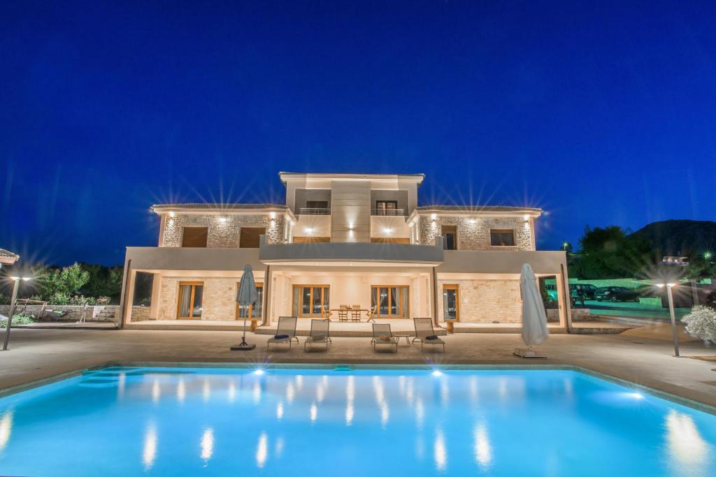 a villa with a swimming pool at night at Petra Luxury Rooms and Apartments in Korinthos