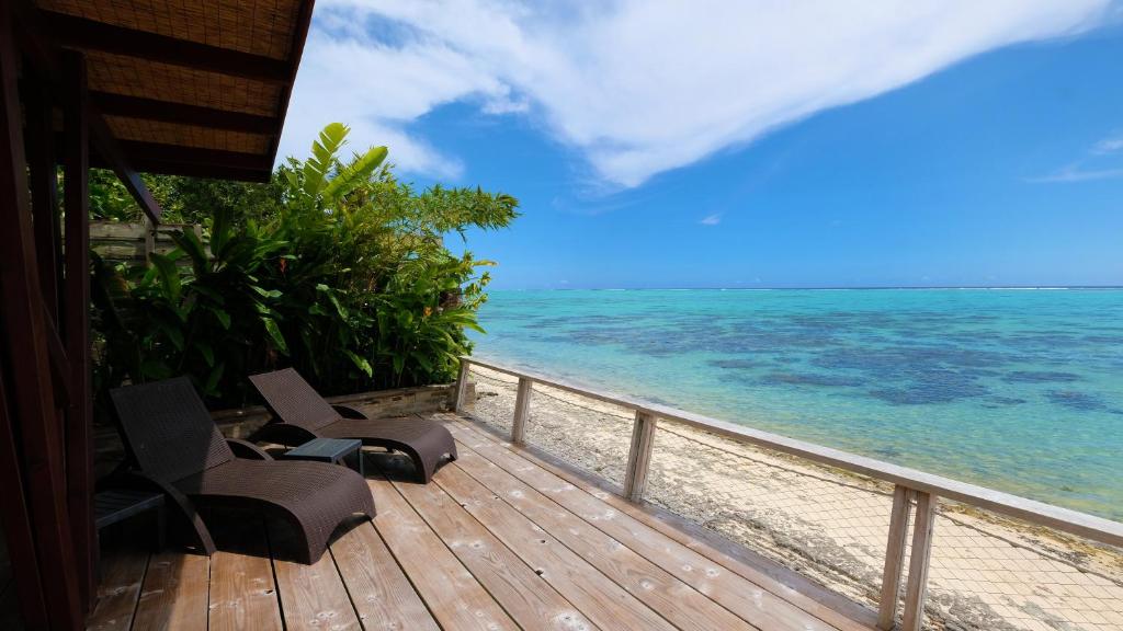 a wooden deck with two chairs on the beach at Villa Miti Vai by ENJOY VILLAS in Iumaru