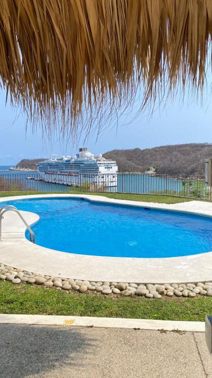 a large blue swimming pool with a cruise ship in the background at Condos Cruz del Mar in Santa Cruz Huatulco