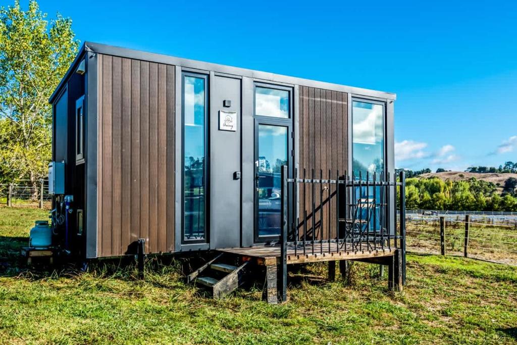 a tiny house sitting on top of a field at Black Horse Cabin 1 by Tiny Away in Parakakau