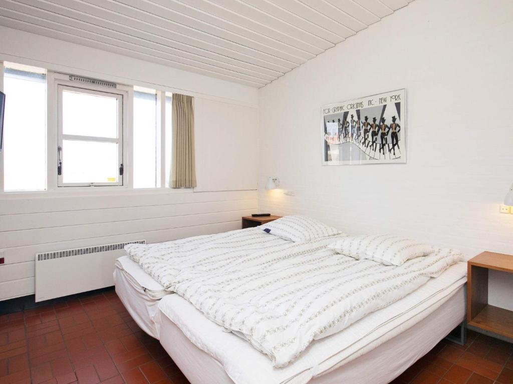 a white bedroom with a large bed and a window at 6 person holiday home on a holiday park in Sæby in Sæby