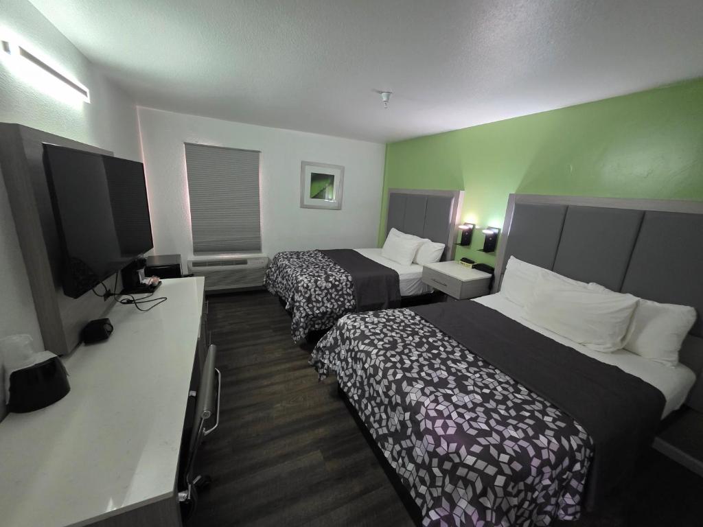 a hotel room with two beds and a flat screen tv at The Aqua Pacific Hotel in Santa Cruz