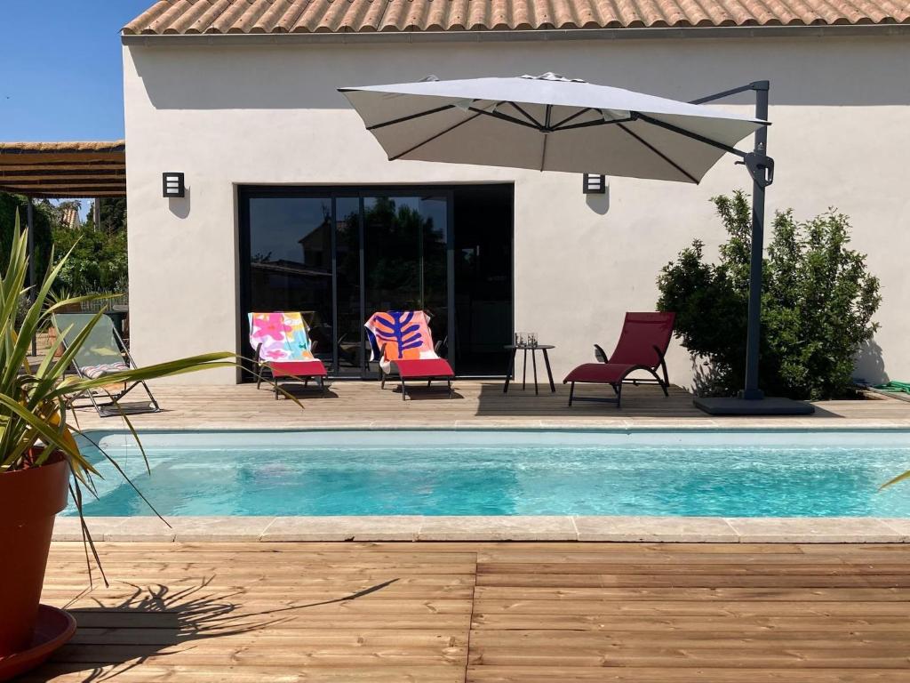 une piscine avec des chaises et un parasol à côté d'une maison dans l'établissement Villa in Sainte Valière with Private Pool, à Sainte-Vallière
