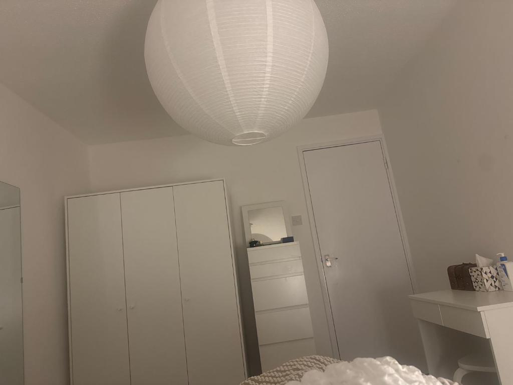 Una habitación blanca con una lámpara blanca y un espejo. en Home stay, en Moffat