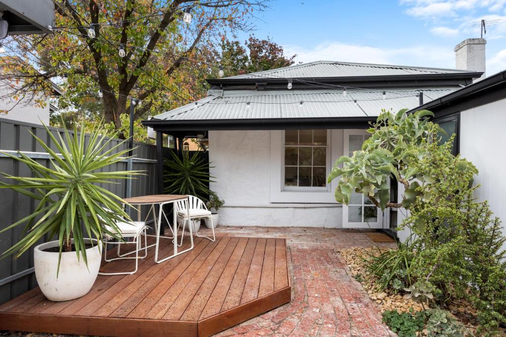 eine Terrasse mit einem Tisch und Stühlen sowie ein Haus in der Unterkunft The Velvet Cottage in Adelaide