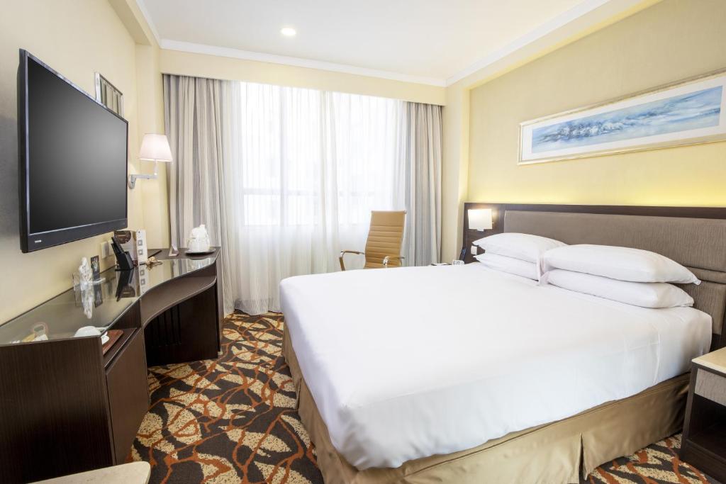 una camera con letto e TV a schermo piatto di Metropark Hotel Kowloon a Hong Kong