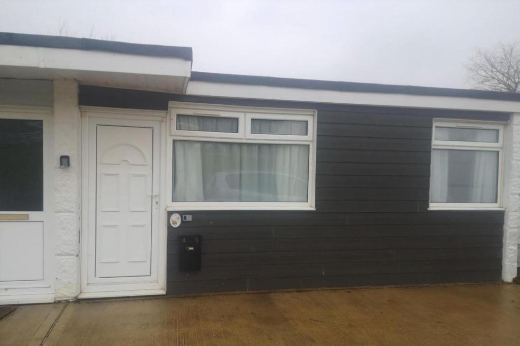 una casa con una puerta blanca y dos ventanas en Lovely Chalet In The Isle Of Wight, Sleeps 6 Ref 97009S, en Sandown