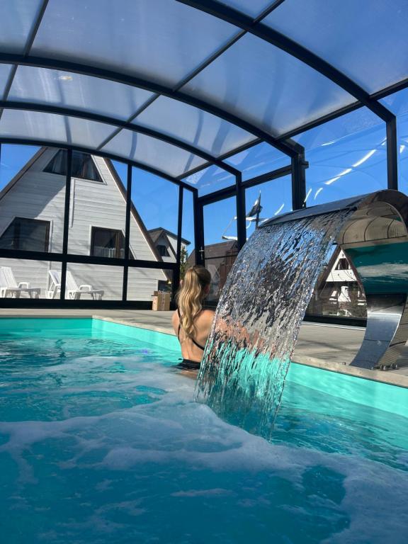 a woman in a swimming pool with a water fountain at Mholiday Sarbinowo u Kaspra in Sarbinowo