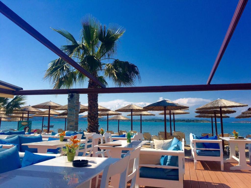 a restaurant with white tables and chairs and the ocean at Vergos Hotel in Vourvourou