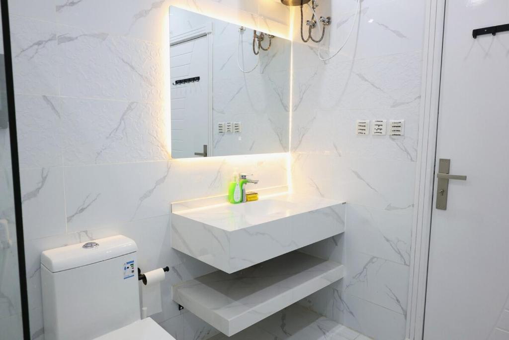 a white bathroom with a sink and a mirror at A spacious apartment with a full kitchen in Al Madinah