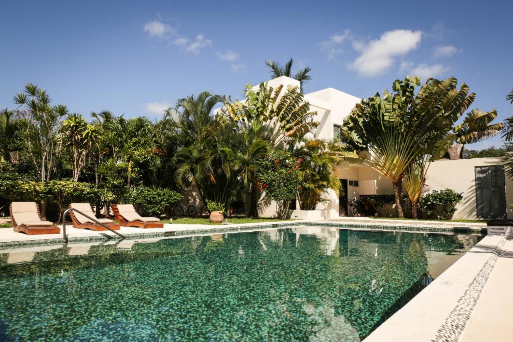 a swimming pool with chairs and a house at Villas H2O in Tulum