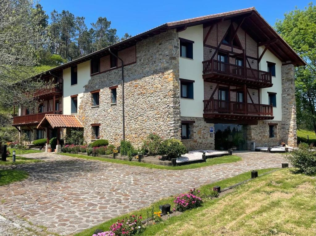 un gran edificio de piedra con balcones y un patio en Hotel-Apartamento Rural Atxurra, en Bermeo